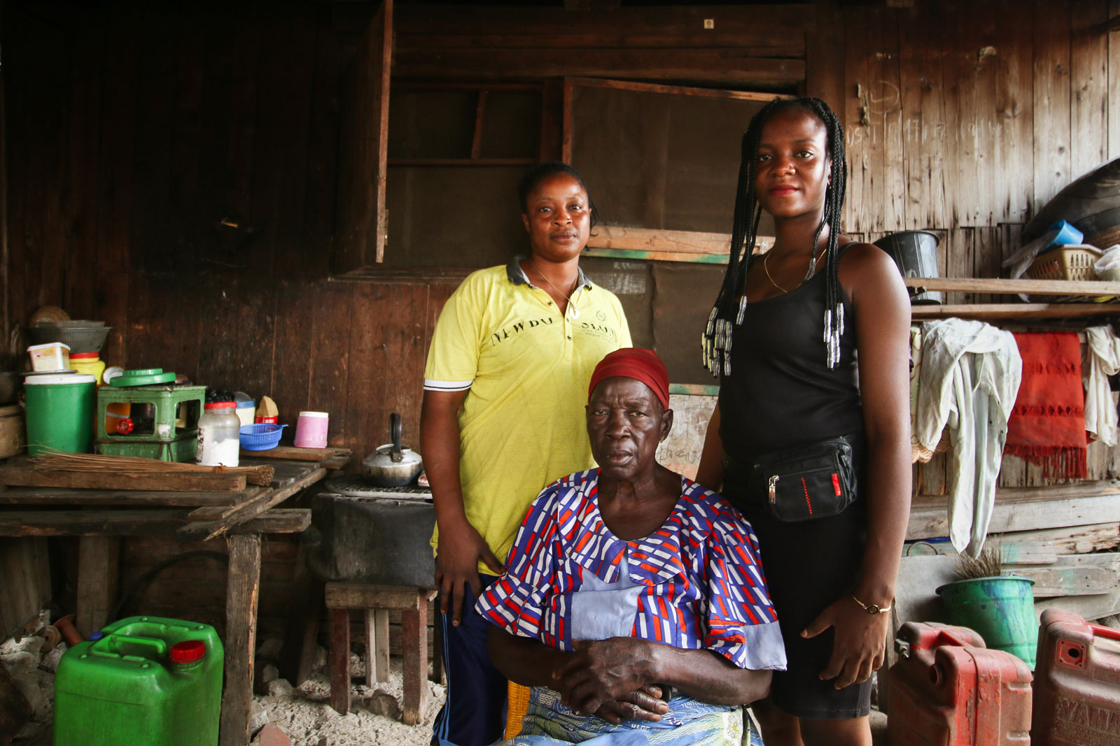 Two women standing and one sitting for a photo portrait inside their one-room apartment