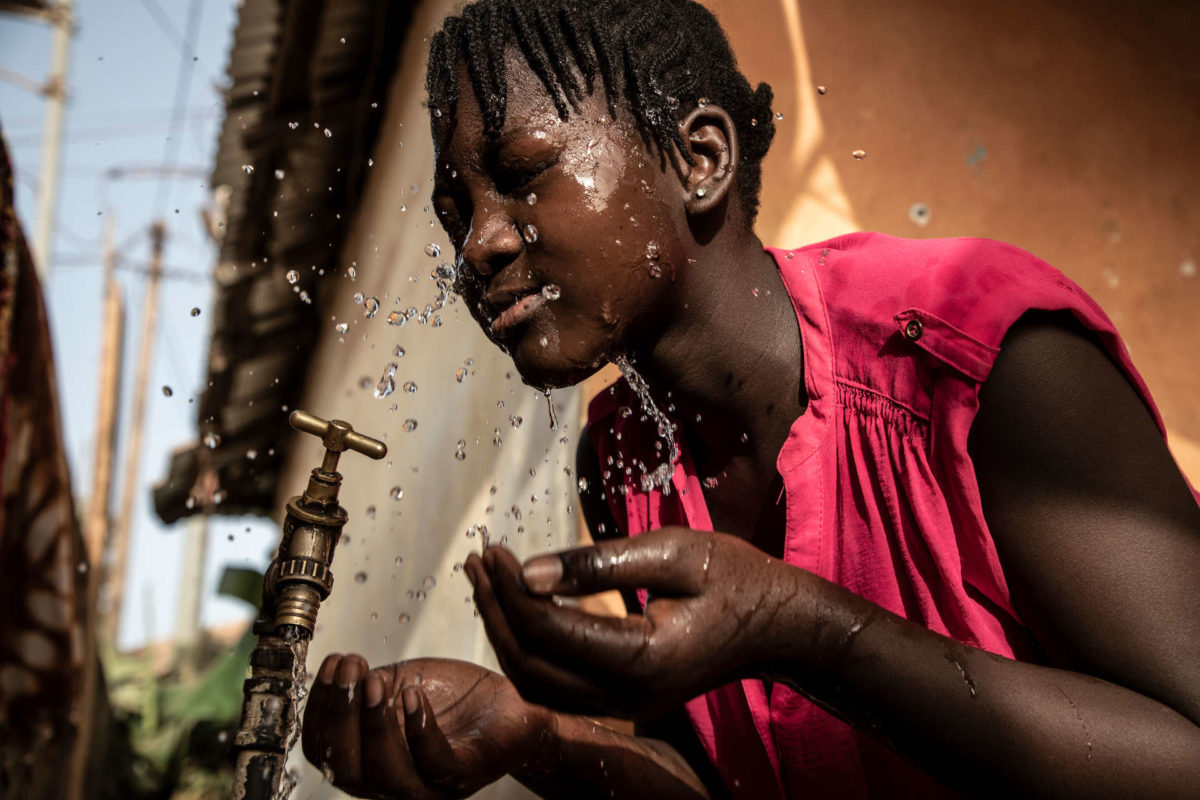 Ya Nima Jaiteh, 14, washes her face at a tap in her family's compound.