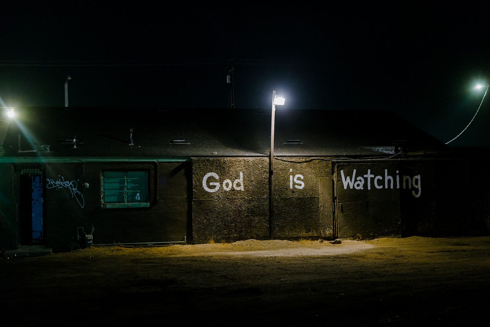 The phrase “God is Watching” is painted on the back of a building occupied by a thrift store in Selma, California.