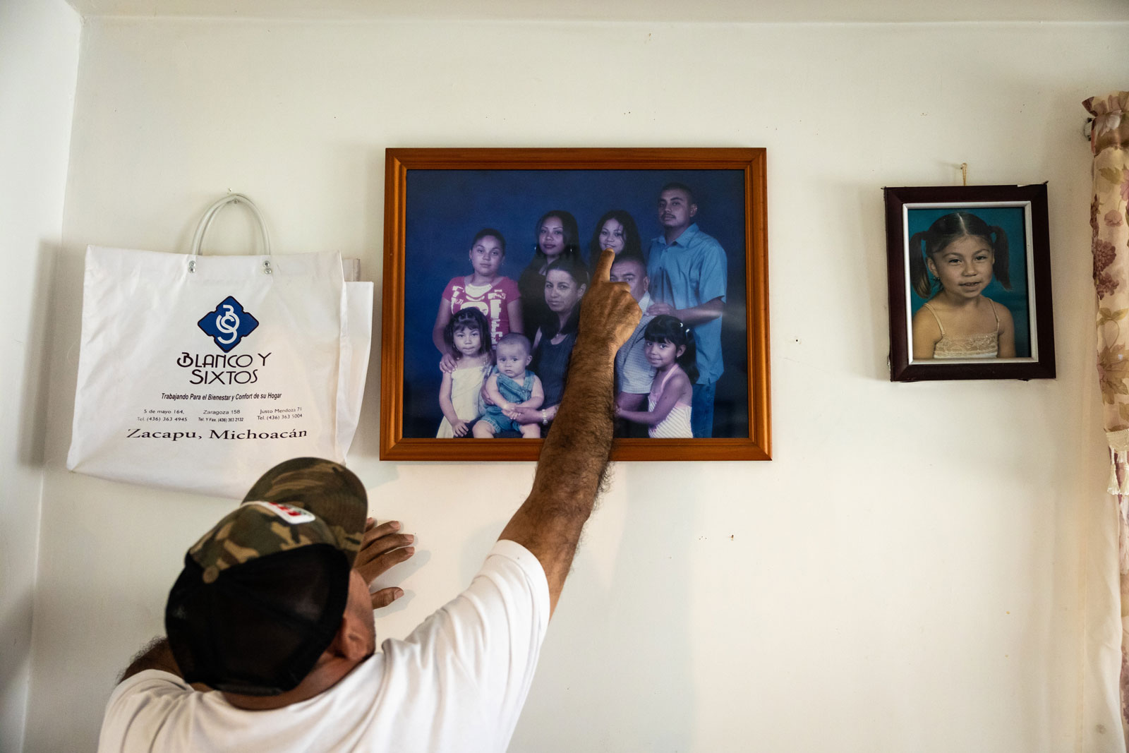 Nicanor Guillen points out his daughter Lupe in a family photo that hangs on a wall.