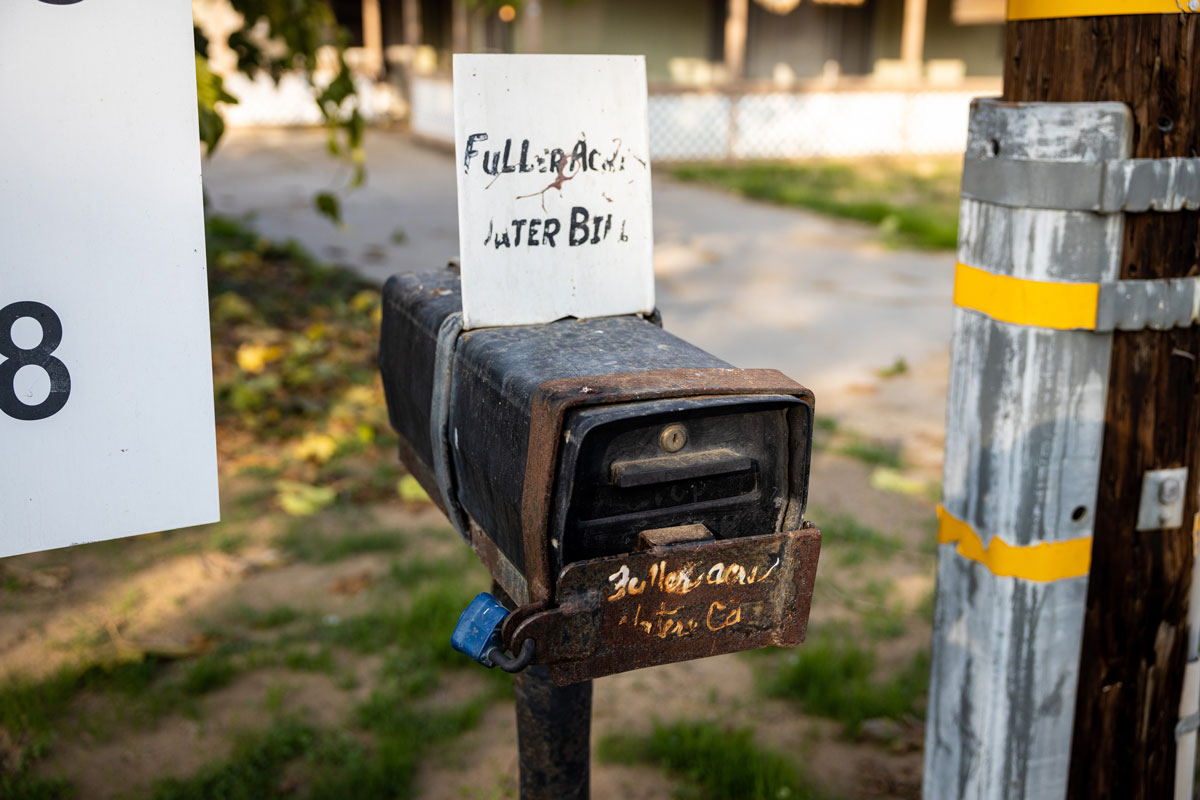 A rusty mailbox with a sign attached to the top that states Fuller Acres Water Bill