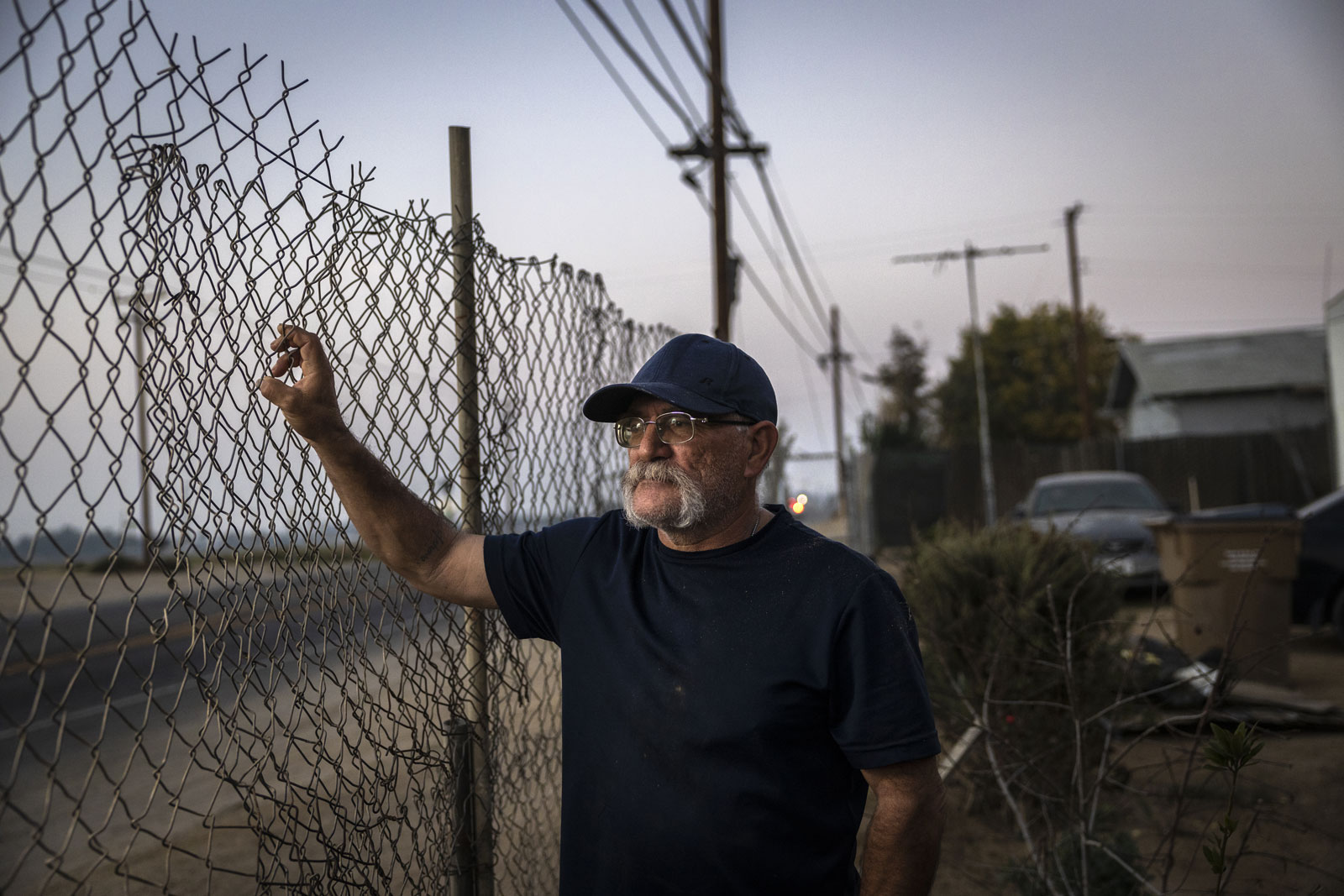 Luis Gomez looks out at the Kern Oil and Refining Co. refinery from his front yard in Fuller Acres.