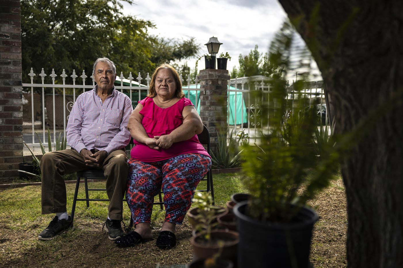 Jose and Gloria Mendoza sit on a bench beneath a pomegranate tree