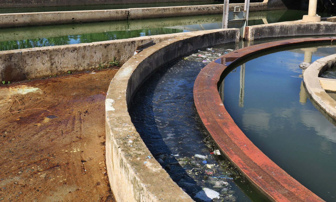 Trash, algae and other debris float in open air containment vessels at the dilapidated wastewater treatment plant in Winburg