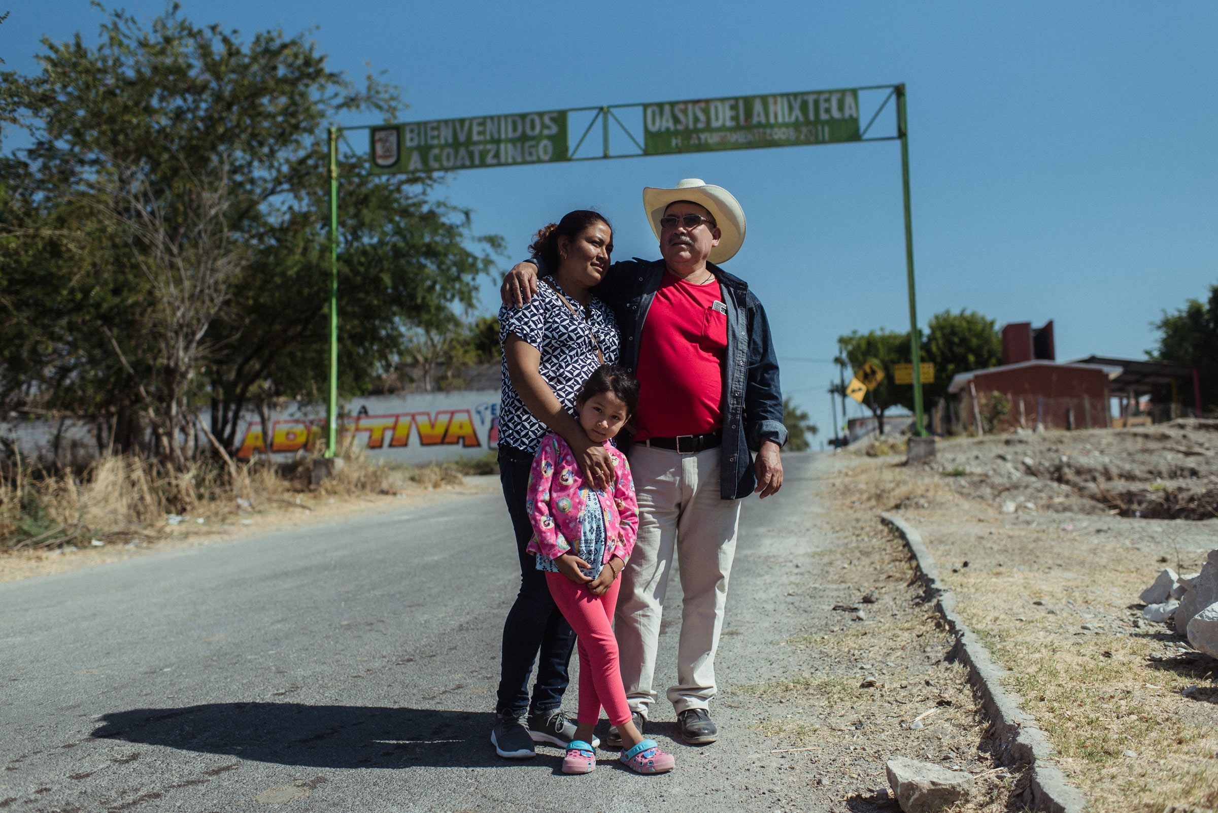 Two parents and a child stand on the side of a road for a portrait
