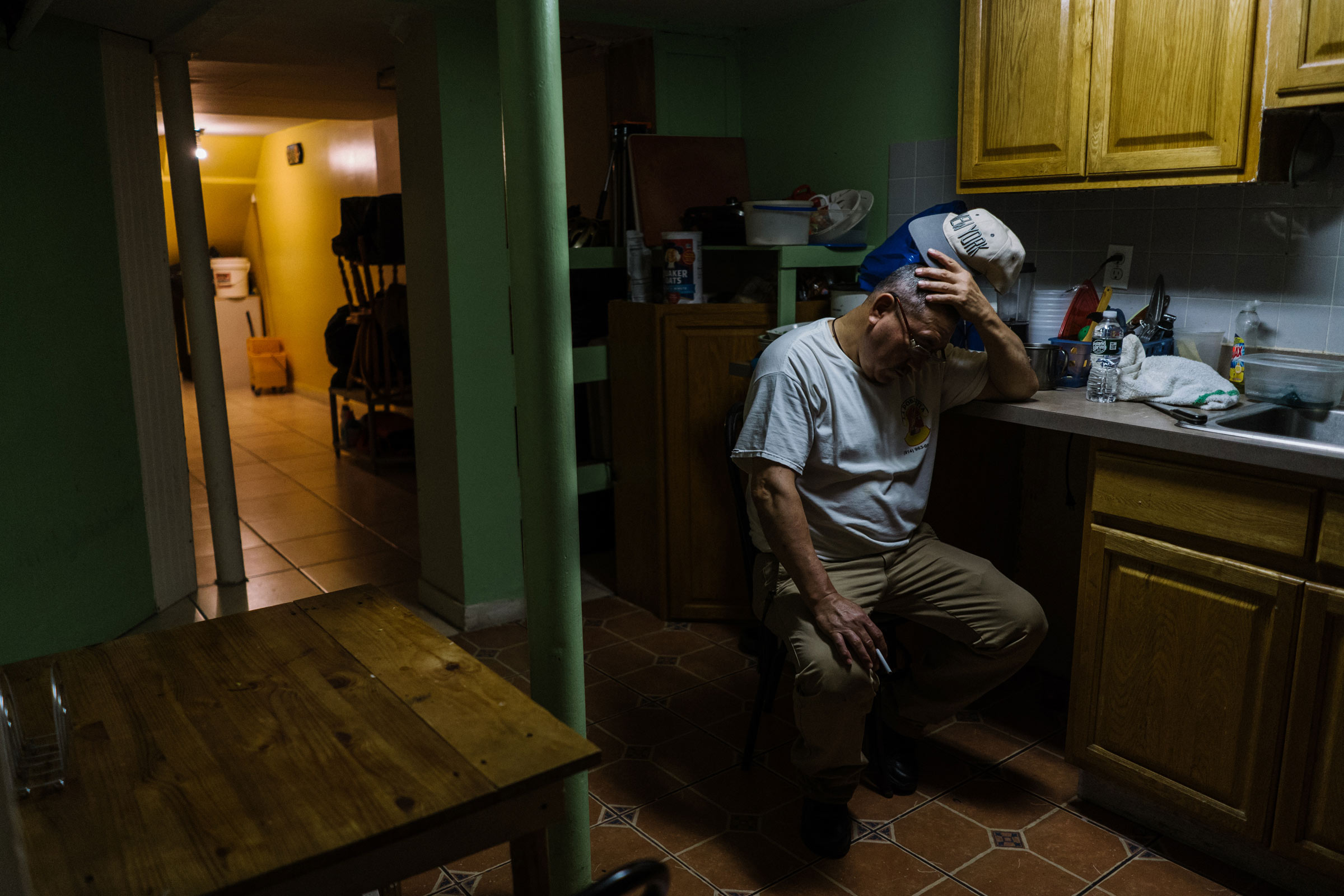 Man sitting with his head in his hand leaning against a counter in a home