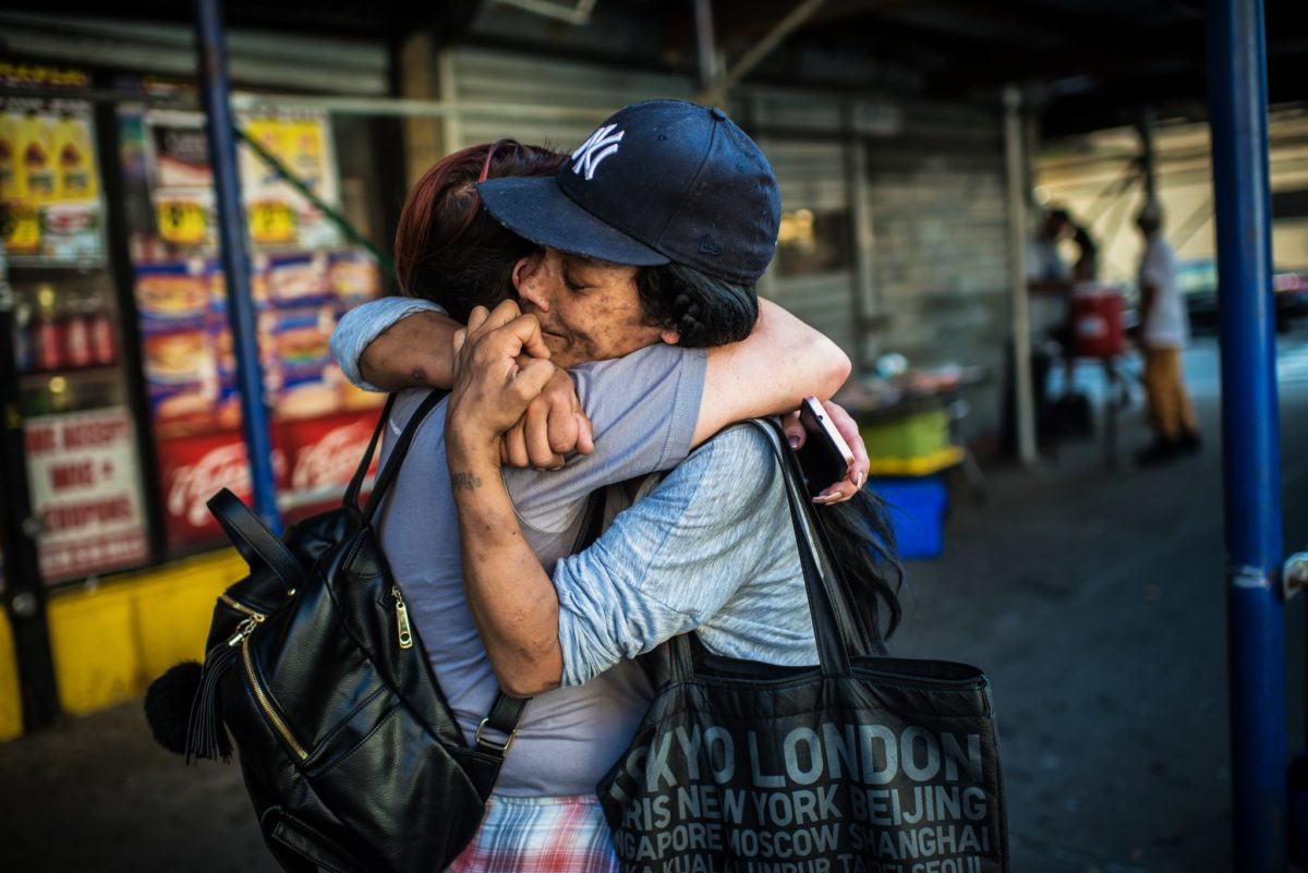 Two people hugging while standing on a street